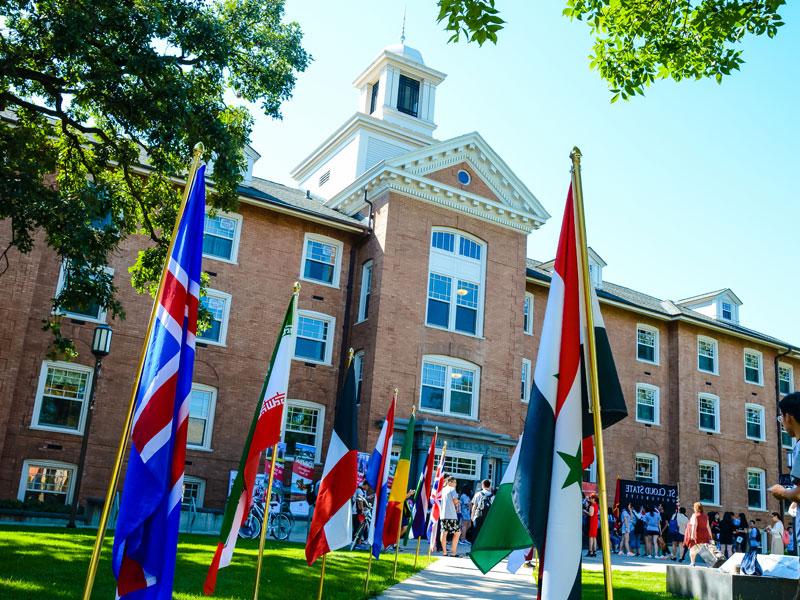 a front exterior view of Lawrence Hall with flags and students visiting