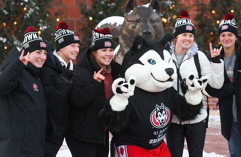 St. Cloud State University mascot, Blizzard, with five students making the 'Blizzard' hand sign. 